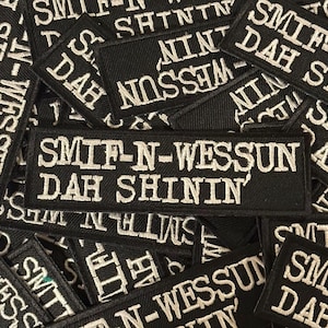 Puede incluir: Un conjunto de parches rectangulares negros con texto bordado en blanco. Los parches presentan la frase "SMIF-N-WESSUN DAH SHININ'" y otros textos relacionados. Los parches son probablemente para ropa o accesorios.