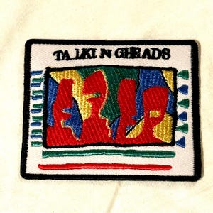 May include: Embroidered patch featuring the words "TALKING HEADS" above a colorful abstract design. The design includes red, blue, yellow, and green shapes. The patch has a white background with a black border.