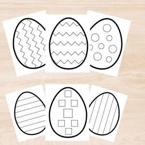 May include: Six white paper sheets with black outlines of Easter eggs. Each egg features a different pattern, including zigzags, dots, and squares, designed for tracing activities. The sheets are arranged on a light wood-grain surface.