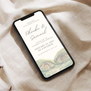 May include: A wedding invitation featuring a charming illustration of two hobbit houses with green roofs and round doors. The invitation reads "Together with their families, Phoebe & Samuel invite you to celebrate their marriage, January 23, 2025 at 4 o'clock, 123 Anywhere St., Any City."