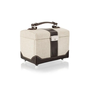 May include: A small, rectangular jewelry box with a handle. The box is beige with dark brown leather accents, including a vertical stripe down the front and trim around the base. It has a silver-colored clasp and small feet.