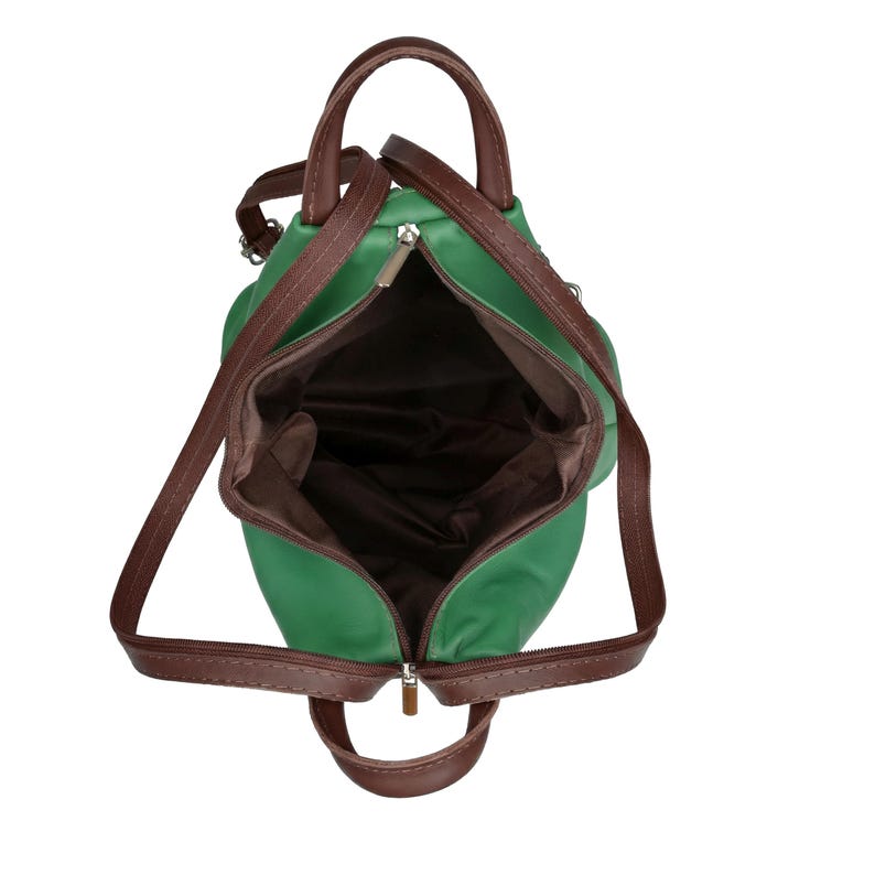 May include: Open green backpack with brown straps and handles. The bag has a zippered main compartment and a brown interior lining. The straps are adjustable, and the bag appears to be made of a smooth material.