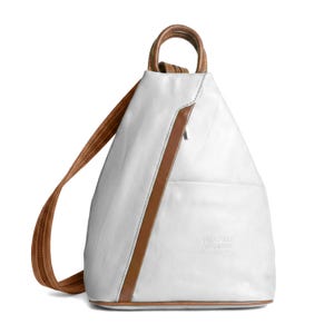 May include: White leather backpack with brown leather trim and straps. The backpack has a top handle and a front pocket. The text "VERA PELLE MADE IN ITALY" is embossed on the front. The bag is a triangular shape.