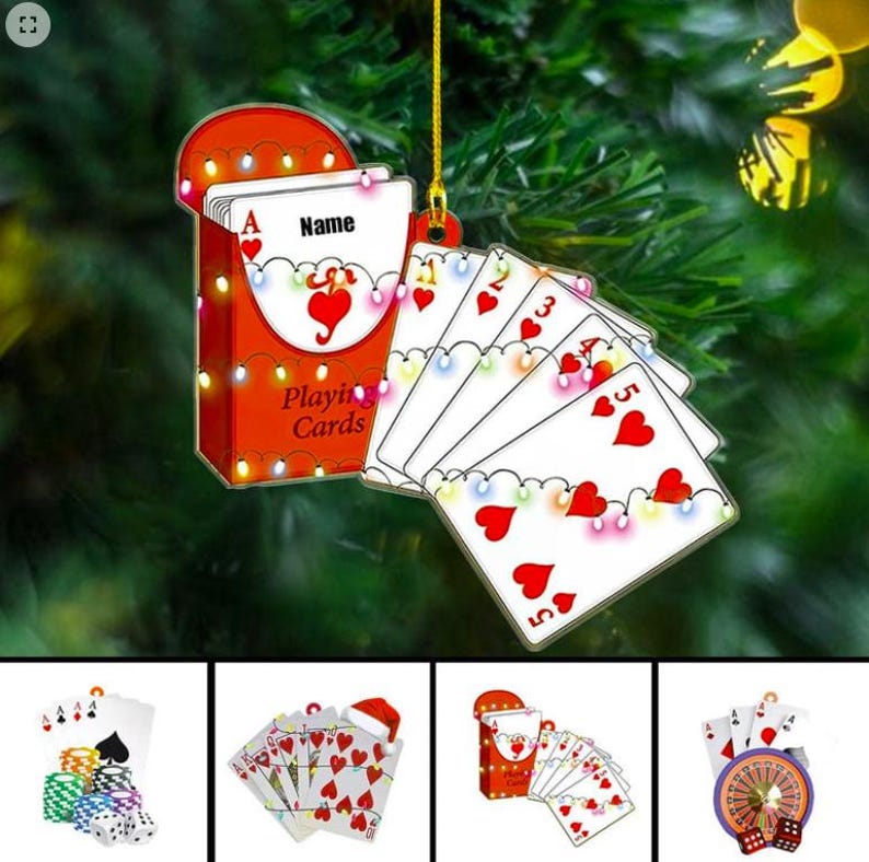 May include: A Christmas ornament featuring a deck of playing cards. The red card case is adorned with string lights and the words "Playing Cards." The cards display hearts and are strung with lights. The top card says "Name."