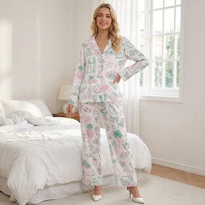 Puede incluir: Conjunto de pijama blanco con un estampado caprichoso con piñas, conos de helado y otras ilustraciones lúdicas en rosa y verde. El conjunto incluye una camisa con botones y pantalones a juego, perfecto para una noche de sueño confortable.