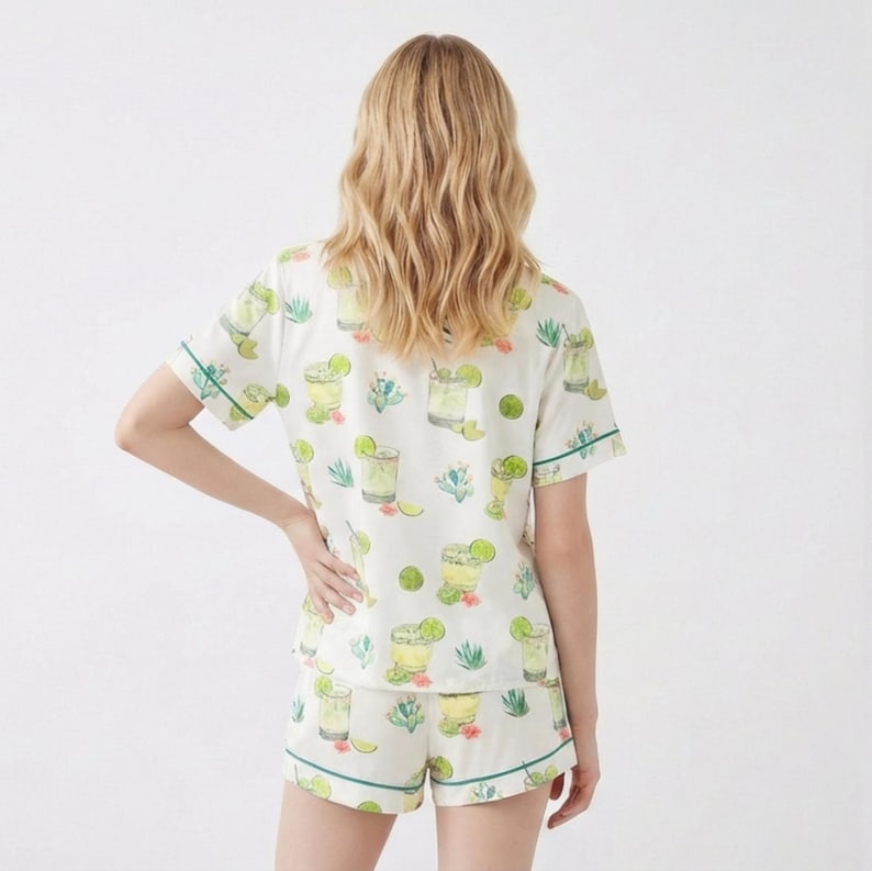 May include: White pajama set with a green trim, featuring a repeating pattern of margarita cocktails, limes, and floral accents. The short-sleeved top and shorts are made of a lightweight fabric.