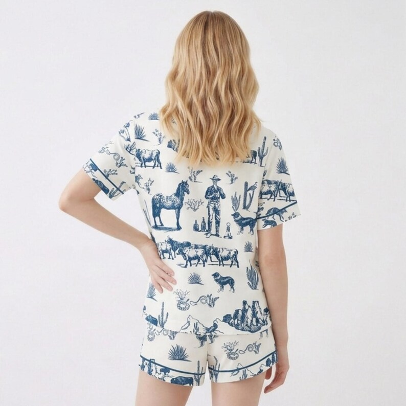 Puede incluir: Conjunto de pijama color crema con estampado azul de tem&aacute;tica western. La camiseta de manga corta y los pantalones cortos presentan ilustraciones de caballos, vaqueros, perros y cactus. El conjunto tiene ribetes azules.