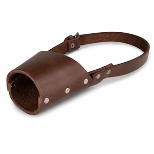 May include: A dark brown leather dog muzzle featuring a cylindrical snout enclosure, a single adjustable strap, and silver-toned metal rivets securing the leather pieces together. The design includes a buckle closure for fastening the strap securely.
