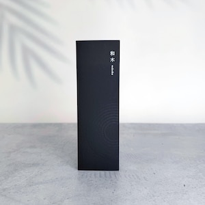 May include: A tall, rectangular black box with a matte finish. The front features the Japanese characters 和木 and the English text waboku printed in white near the top. A subtle, circular ripple pattern is embossed on the lower portion of the box.