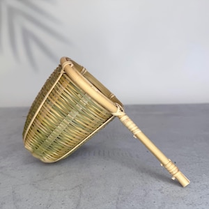 May include: A conical tea strainer crafted from woven bamboo strips, featuring a natural light tan and pale green colour palette. The strainer has a sturdy bamboo rim and a long, slender bamboo handle reinforced with thin, tightly wrapped bamboo cord.