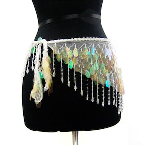 May include: A white mesh belly dance belt with iridescent sequins and beaded strands. The belt has a tie closure and is designed for the waist. The sequins reflect green, yellow, and blue. A decorative accessory.