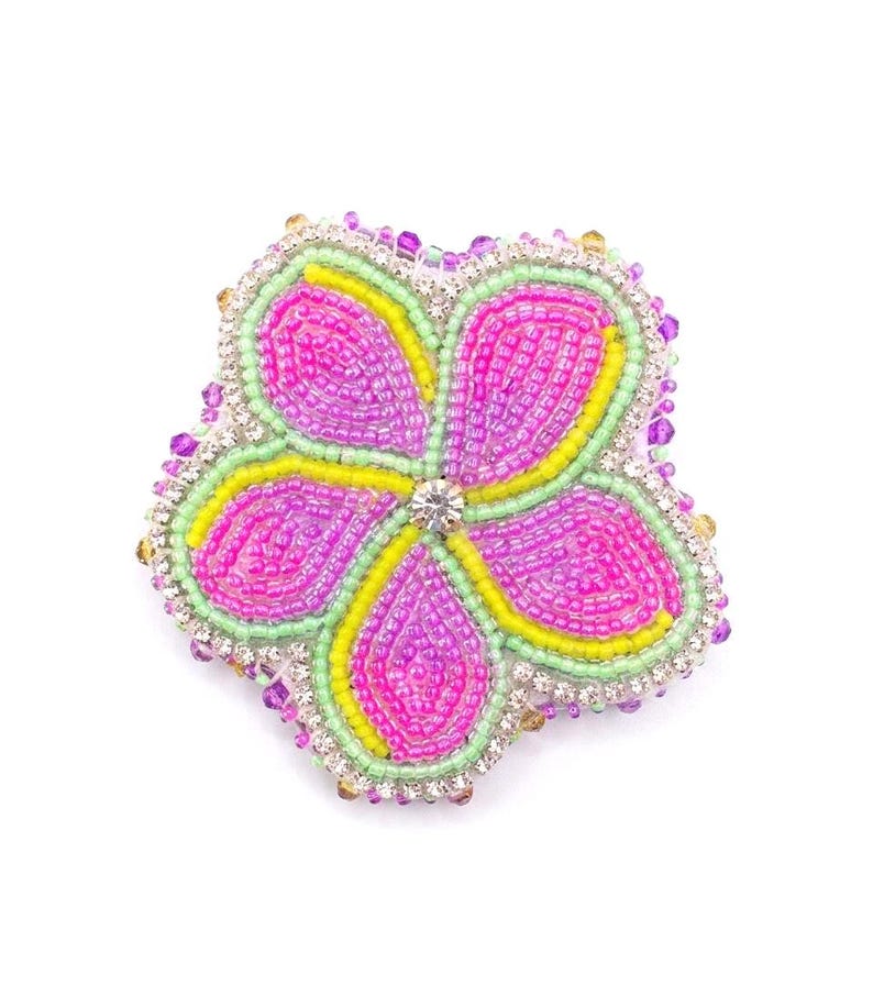 May include: A five-petaled flower brooch crafted with vibrant pink and yellow seed beads. The petals are outlined in light green beads and accented with clear rhinestones along the outer edge, featuring a single clear crystal at the center.