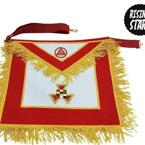 May include: A white and red Masonic apron featuring a triangular flap with a red embroidered symbol, a central square emblem with colorful squares, and long yellow fringe trim along the edges. A red adjustable strap is attached to the top.