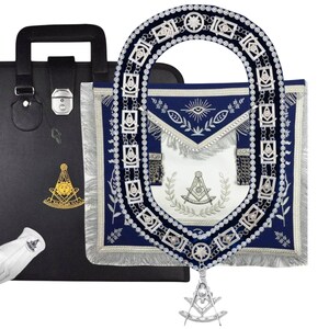 Puede incluir: Un maletín negro con un emblema dorado, guantes blancos y un delantal masónico azul y blanco con una cadena y colgante plateados. El delantal tiene flecos y símbolos bordados.