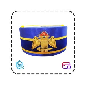 Puede incluir: Gorra azul con bordados dorados que representan un águila, una espada y el número 32. La gorra tiene una banda y un ribete dorados. Es un sombrero ceremonial.