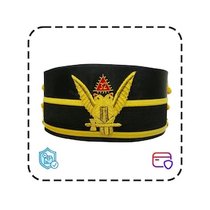 Puede incluir: Un sombrero negro con ribete dorado y un emblema dorado detallado con un águila, una espada y el número 32 dentro de un triángulo. El sombrero tiene forma cilíndrica y probablemente sea ceremonial.