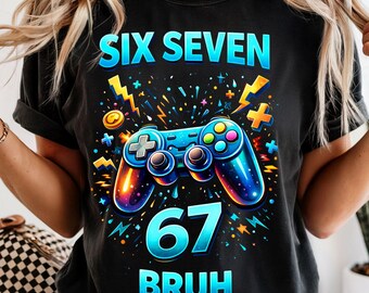 May include: Black t-shirt with a colorful video game controller graphic. The design includes the text "SIX SEVEN 67 BRUH" in blue and yellow, with lightning bolt and star accents. The controller has colorful buttons.