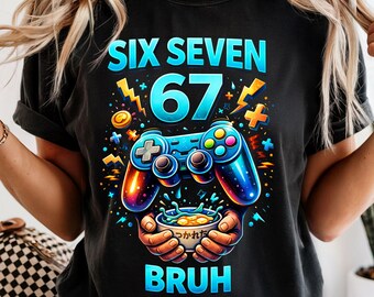 May include: Black t-shirt with a colorful graphic design. The design features the words "SIX SEVEN 67 BRUH" in blue and white, along with a video game controller and other gaming-related elements. The shirt is a casual wear item.