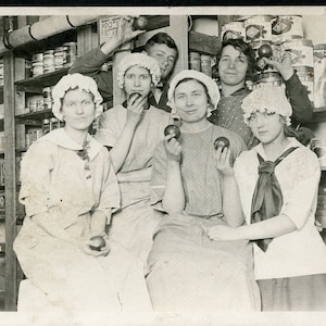 Comiendo manzanas en la tienda familiar en la década de 1910. Postal con foto real.