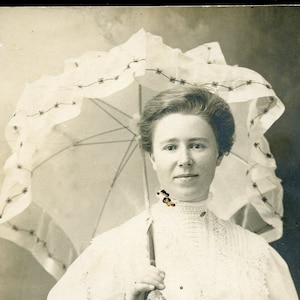 Bella donna in ABITO BIANCO DI COTONE che tiene un parasole in una cartolina fotografica del 1910