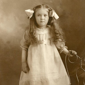 Jolie petite fille avec des tresses et des rubans dans les cheveux - Carte postale photo originale des années 1910