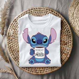 Puede incluir: Camiseta blanca con un personaje azul Stitch sosteniendo una taza de caf&eacute; que dice "Monday Mood".