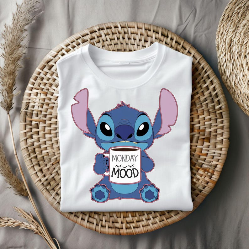 Puede incluir: Camiseta blanca con un personaje azul Stitch sosteniendo una taza de caf&eacute; que dice "Monday Mood".