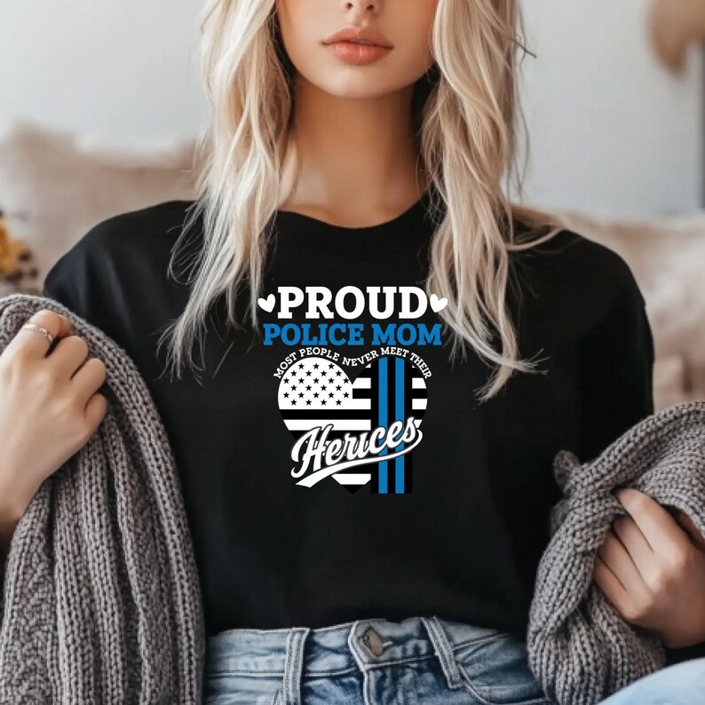 May include: Black t-shirt with a white heart design that says "Proud Police Mom" and "Most People Never Meet Their Heros".