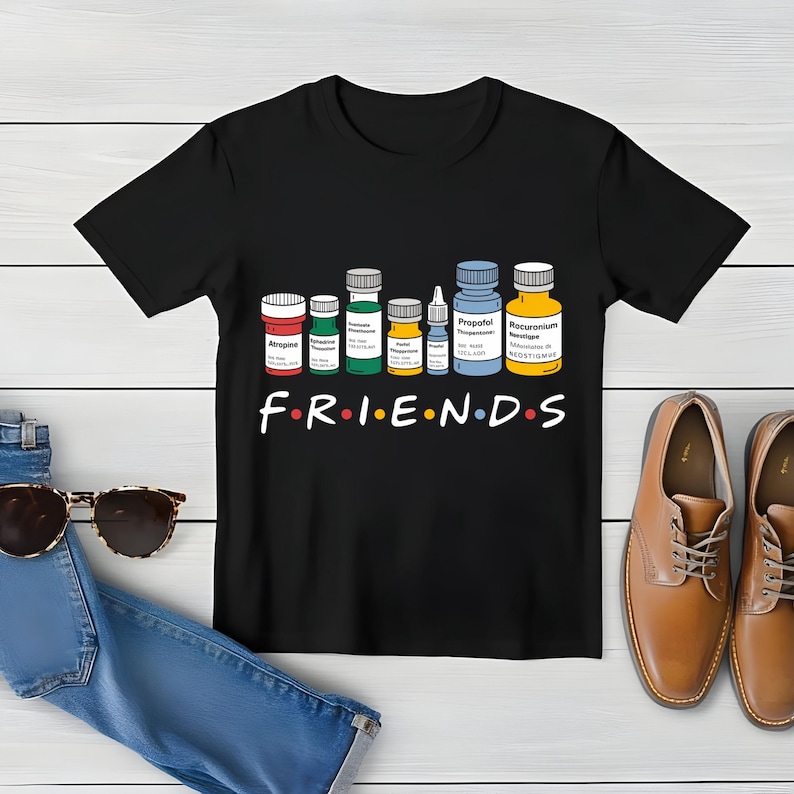 May include: Black t-shirt with a graphic of various medicine bottles and the word "FRIENDS" in a stylized font. The bottles are labeled with names like "Atropine", "Propofol", and "Rocuronium".