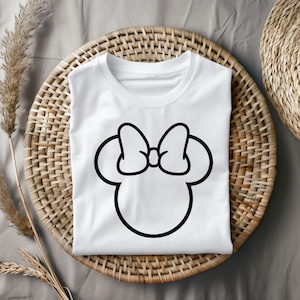 Pu&ograve; includere: Maglietta bianca con un contorno nero della testa e del fiocco di Minnie Mouse.