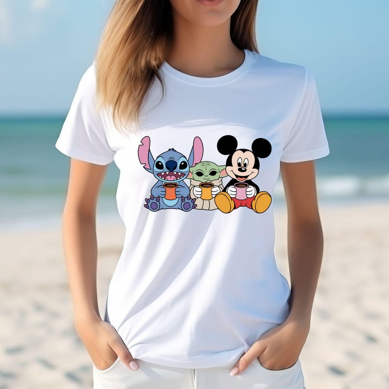 Puede incluir: Camiseta blanca con un gr&aacute;fico de Stitch, Baby Yoda y Mickey Mouse sosteniendo tazas de caf&eacute;.