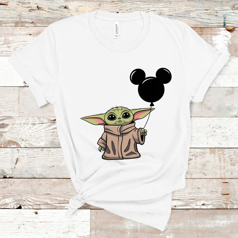 K&ouml;nnte beinhalten: Wei&szlig;es T-Shirt mit einer gr&uuml;nen Figur, die einen schwarzen Mickey Mouse-Ballon h&auml;lt.