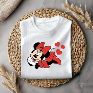 May include: White t-shirt with a red and black cartoon image of Minnie Mouse with a red bow. Three red hearts are above Minnie Mouse.