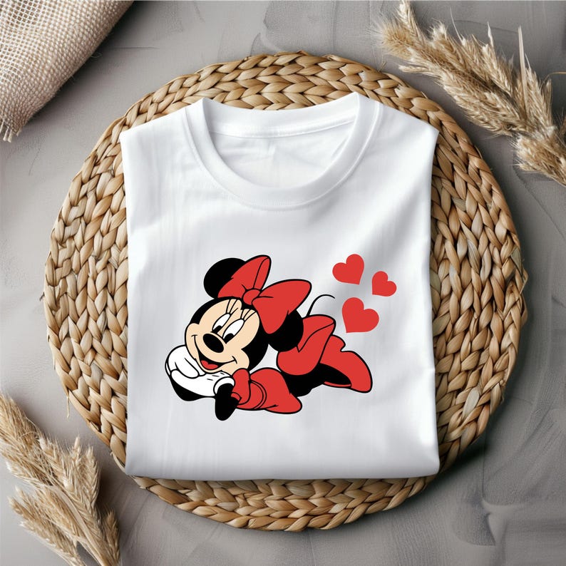 May include: White t-shirt with a red and black cartoon image of Minnie Mouse with a red bow. Three red hearts are above Minnie Mouse.