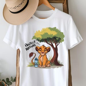 May include: White t-shirt with a cartoon lion cub holding a water bottle. The lion cub is sitting under a green tree. The text "Protect Nature" is printed on the shirt.