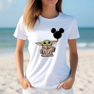 K&ouml;nnte beinhalten: Wei&szlig;es T-Shirt mit einer gr&uuml;nen Comicfigur, die einen schwarzen Mickey-Maus-Ballon h&auml;lt.