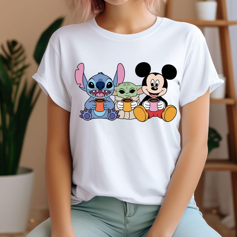 Puede incluir: Camiseta blanca con un gr&aacute;fico de Stitch, Baby Yoda y Mickey Mouse sosteniendo tazas de caf&eacute;.