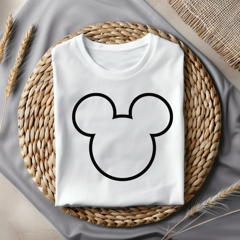 Pu&ograve; includere: Maglietta bianca con un contorno nero delle orecchie di Topolino.
