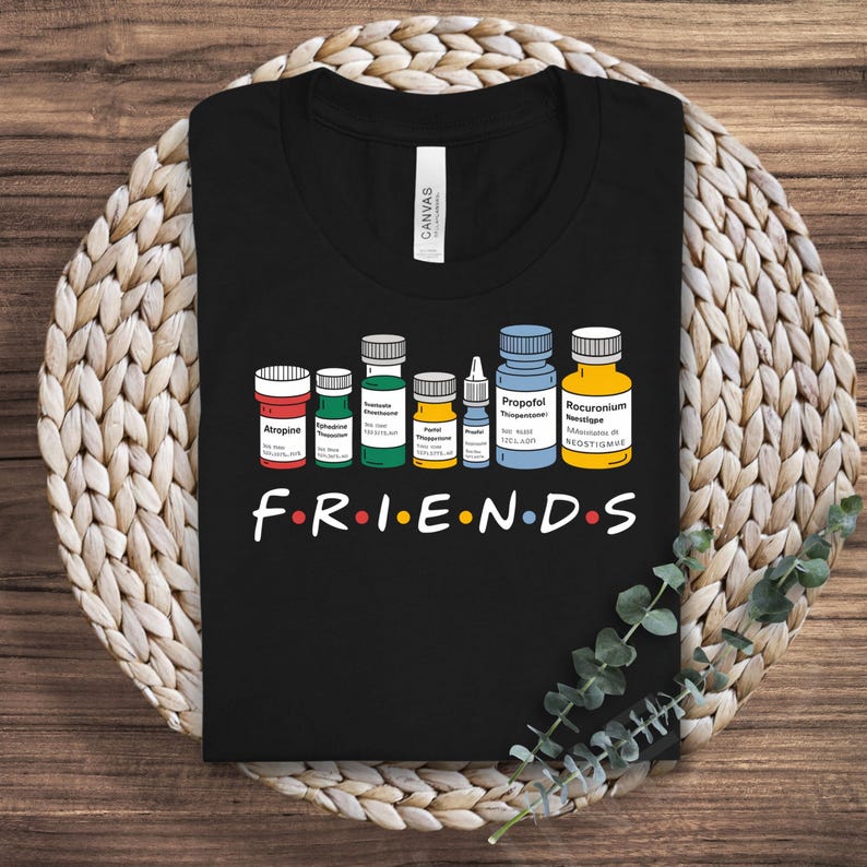 May include: Black t-shirt with a graphic of various medicine bottles and the word "FRIENDS" in a stylized font.