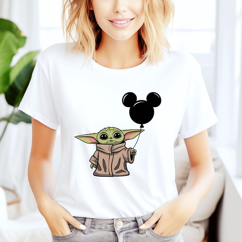 K&ouml;nnte beinhalten: Wei&szlig;es T-Shirt mit einer gr&uuml;nen Alienfigur, die einen schwarzen Mickey-Maus-Ballon h&auml;lt.