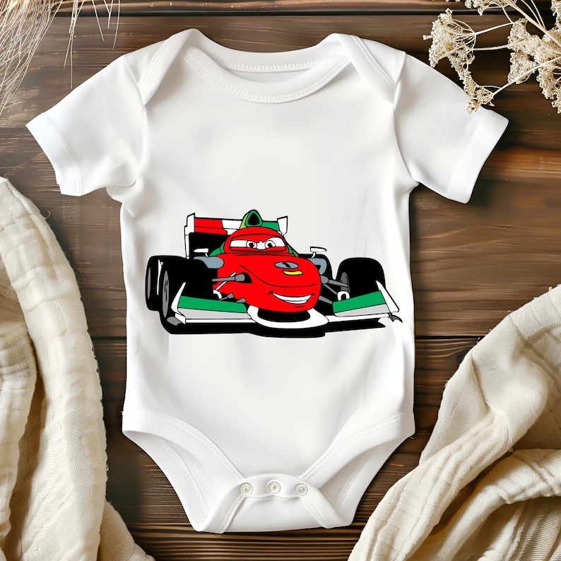 May include: White baby onesie featuring a cartoon image of a red racing car with green and white accents. The car has a smiling face and is driving on a race track.