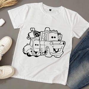 May include: White t-shirt featuring a black and white illustration of a tow truck and a car. The tow truck has a hook and a smiling face. The car is also smiling.