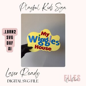 May include: A yellow, cloud-shaped sign featuring the text My Wiggles House in red, blue, and purple layered lettering. The sign includes a small pink tag to the left listing file formats .LBRN2, SVG, DXF, and AI for laser cutting projects.