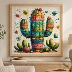 Op de afbeelding: Een ingelijst kruissteekkunstwerk met een kleurrijk cactusontwerp. De cactus is afgebeeld met levendige tinten groen, blauw, oranje en roze, omringd door decoratieve bloemen en kleinere cactussen. Het kunstwerk wordt tentoongesteld op een houten tafel.