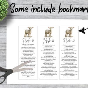 May include: Three rectangular paper bookmarks featuring a graphic of a lamb at the top and the text of Psalm 23 printed below. The bookmarks are arranged side-by-side on a white sheet, with a pair of black scissors positioned over the left bookmark.