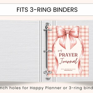 May include: A white 3-ring binder with a pink and white plaid journal insert. The journal cover features a pink bow and the words "my PRAYER Journal". Text at the top reads "FITS 3-RING BINDERS".