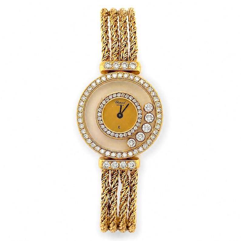 May include: A gold wristwatch featuring a round face with a smaller inner gold dial, surrounded by a ring of clear stones. Five loose clear stones are set between the inner and outer dials. The band consists of three braided gold rope strands.