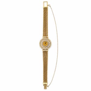 May include: A gold-tone watch featuring a round face with a mustard yellow dial, surrounded by a bezel set with clear stones. The band consists of four parallel twisted gold-tone chains, and a thin safety chain is attached to the side of the watch.