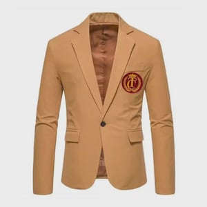 May include: A tan blazer with a single-button closure and a notched lapel. The blazer features a crest emblem on the chest and two front pockets. The interior lining is a darker shade of brown.