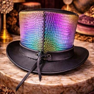 May include: A black top hat with a rainbow-coloured, textured crown. The crown has a reptile-like pattern and is stitched down the back. The hat has a black brim and a black band around the crown. Black ribbons hang from the side.